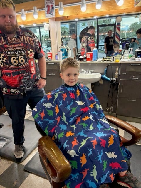 The same boy smiling after his haircut by Kyle Wason, Master Barber